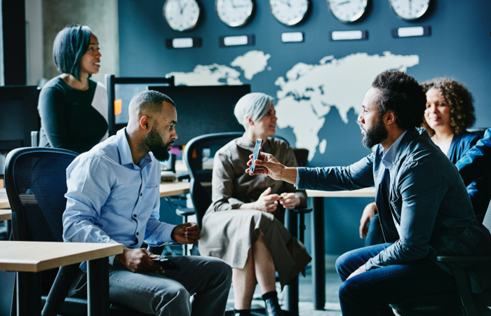 Businessman showing coworker data on smartphone