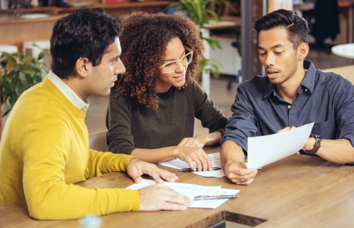 Three people discussing paperwork