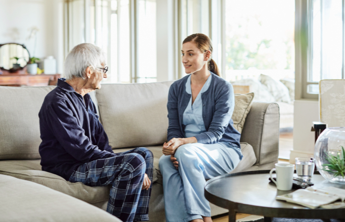 Senior man talking to nurse on couch