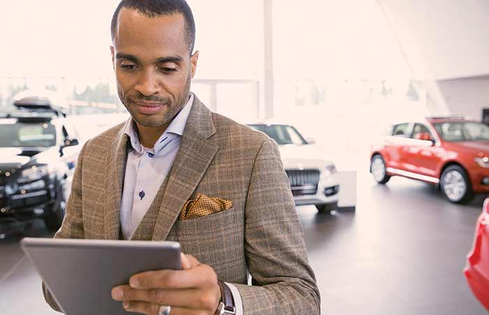 Car Dealer Looking at Tablet on Showroom Floor