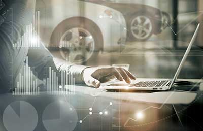 Car Dealer Working on Laptop Screened Bar Charts