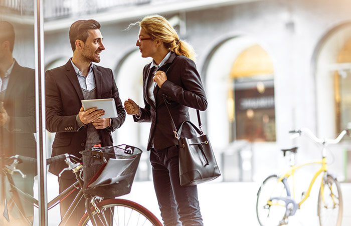 Businessman With Bicycle Talking To Colleague