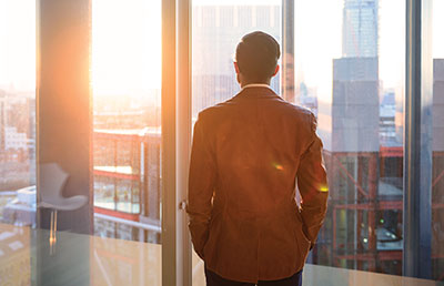 Businessman Looking Out Window at City Skyline