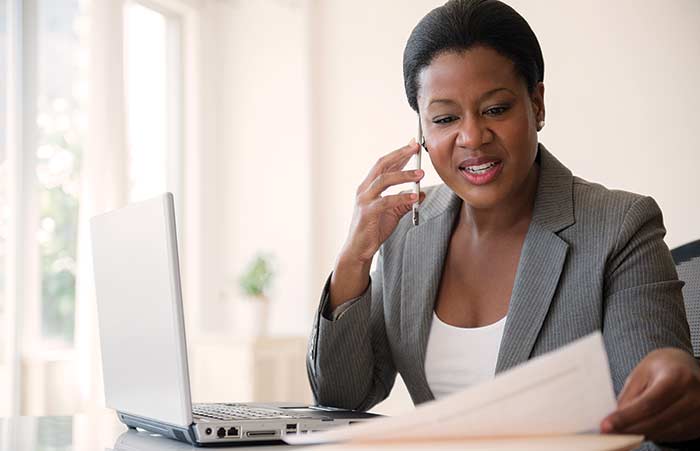 Businesswoman Using Cell Phone While Looking at Paper