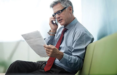 Man Sitting on Couch Discussing Paperwork Over Phone