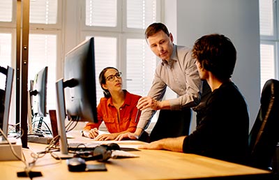 Three Discuss At Workstation