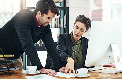 Two Business People Discuss Document at Desk