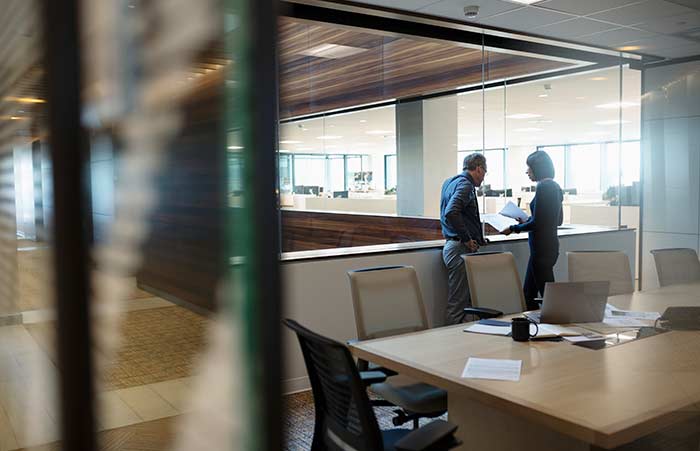 Two Discuss Paper By Conference Room Glass