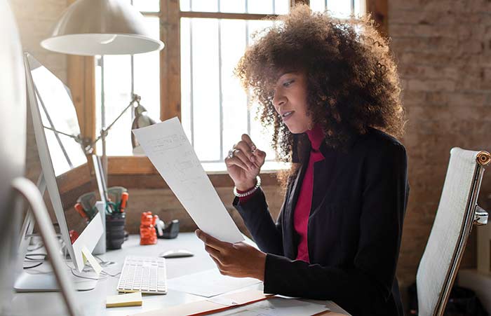 Woman Working at Desk Holding Paper