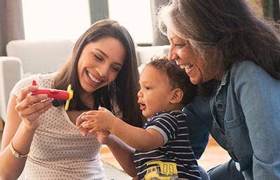Mother and Grandmother Playing with Baby on Floor