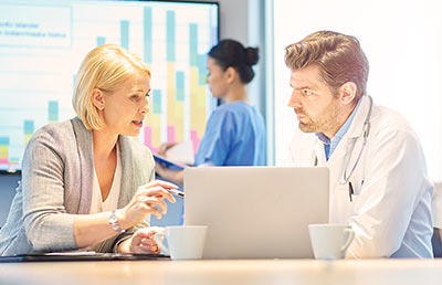 Adminstrator Talking to Doctor Charts in Background