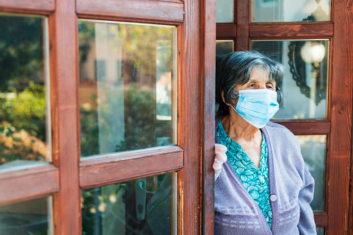 Elderly Woman With Mask Standing By Door