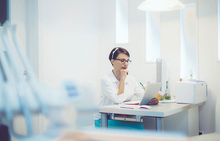 Female Dentist Looking at Tablet at Desk