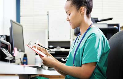 Woman at Nurses Station Looking at Chart