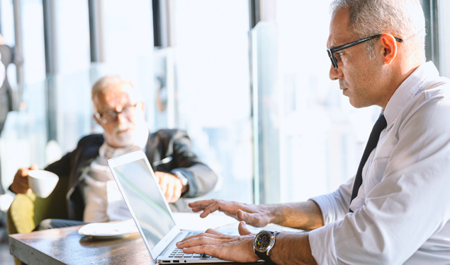 Portrait of pensive mature businessman using laptop