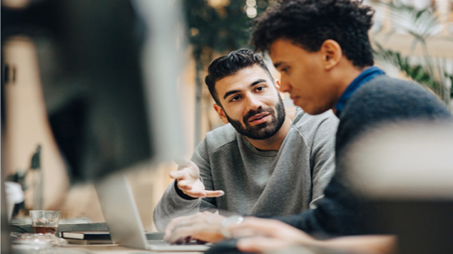 Computer programmers discussing over laptop
