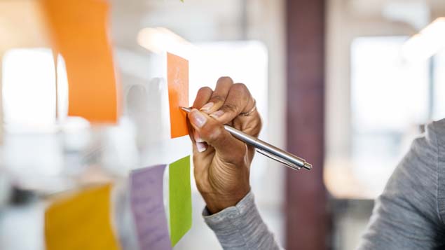 Female writing new ideas on sticky note