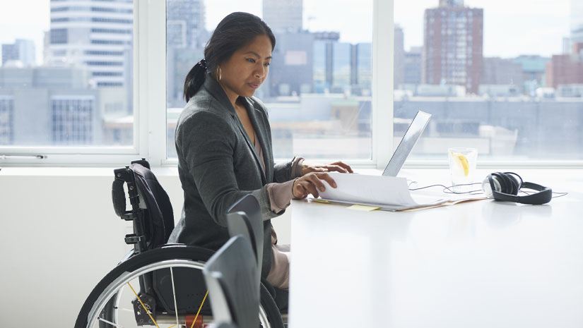 Businesswoman with disability reviewing work on laptop