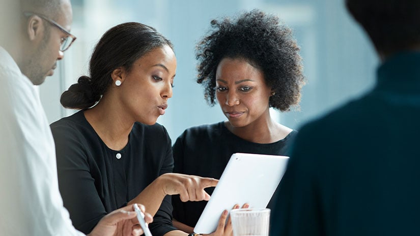 Group of coworkers standing around desk and having meeting