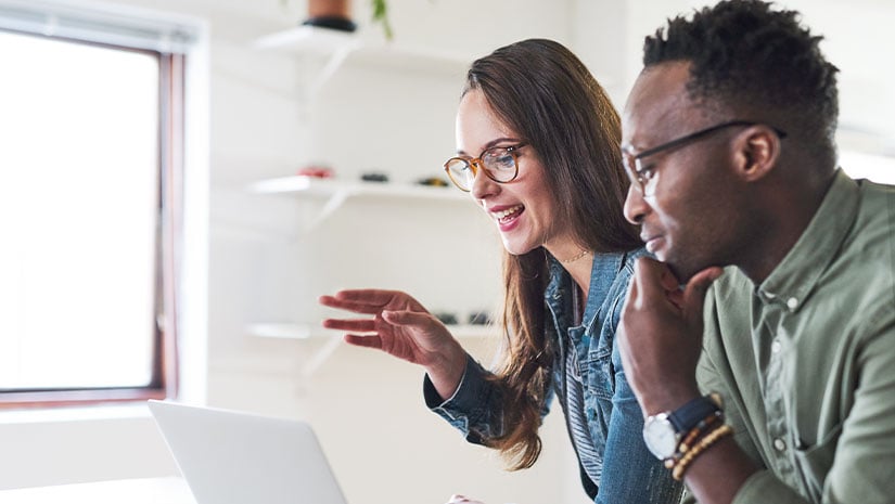 Shot of a young businessman and businesswoman using a laptop in a modern office