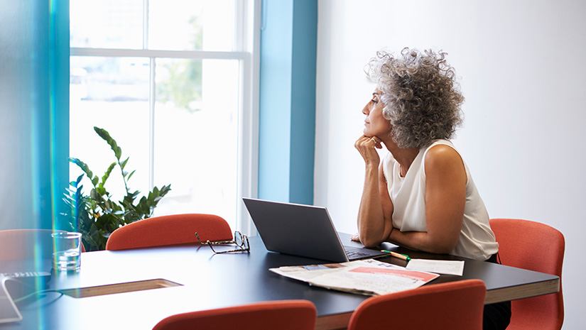 Middle aged woman looking out of the window in the boardroom