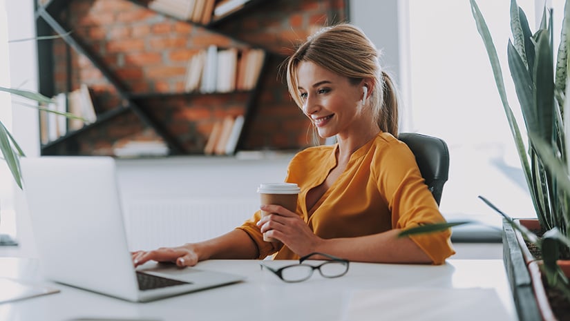 Person working at desk smiling with a coffee