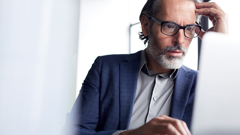 Serious businessman with head in hand using laptop computer