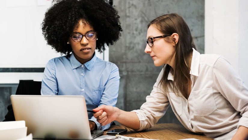 Two young women having a discussion in a conference room
