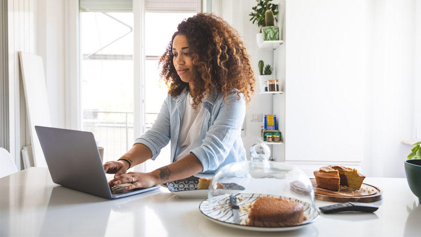 Woman working from home on laptop in her bright kitchen
