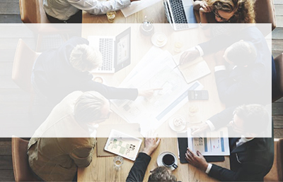 An overhead shot of a team of people at a conference table reviewing future plans and forecasts.