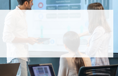 A team in an office reviews data on a screen in a boardroom.