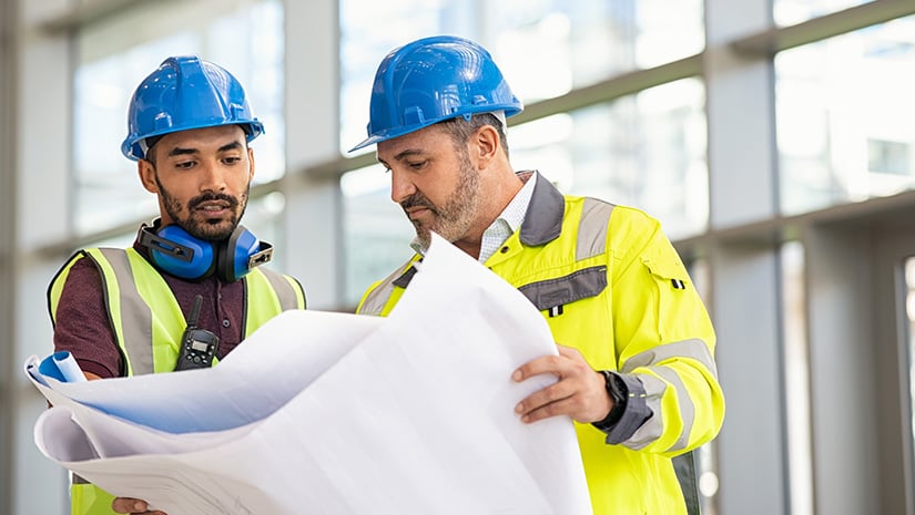 Construction site worker and engineer discussing on blueprint project