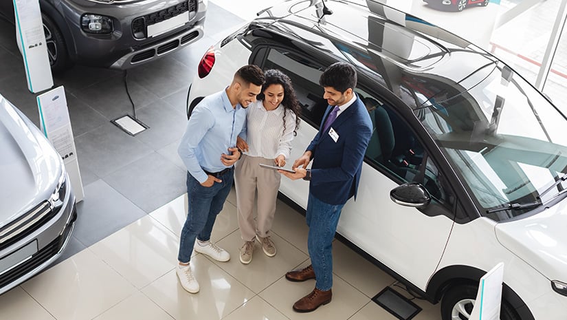 Customers having conversation with sales assistant buying car