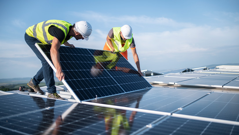 Two engineers installing solar panels on roof