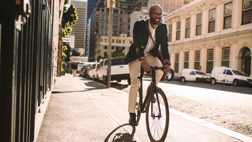 Young smiling businessman going to work by bike.