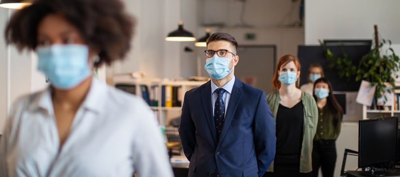 Coworkers together in an office wearing masks.