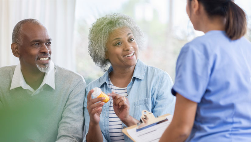 Confident senior African American woman gestures as she asks a female healthcare professional a question about her prescription medication.
