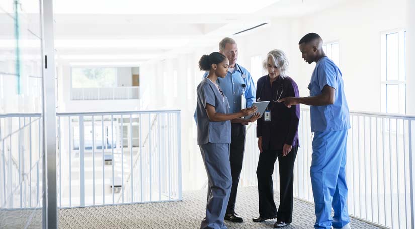 Doctor and nurses discussing information from digital tablet.
