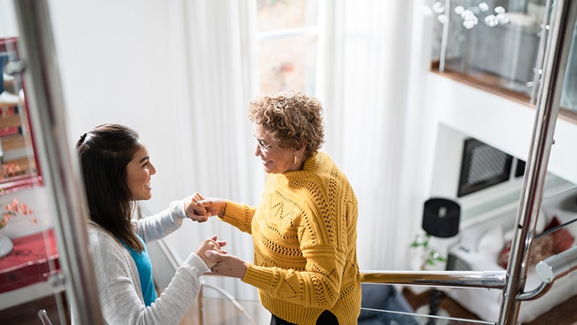 Nurse supporting senior patient walking or moving up the stairs at home