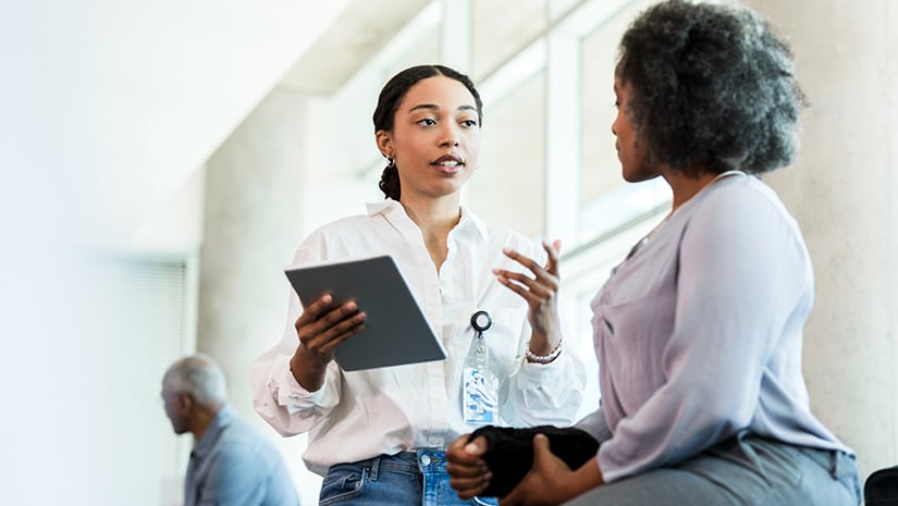Physical therapist gestures while asking woman questions about injury