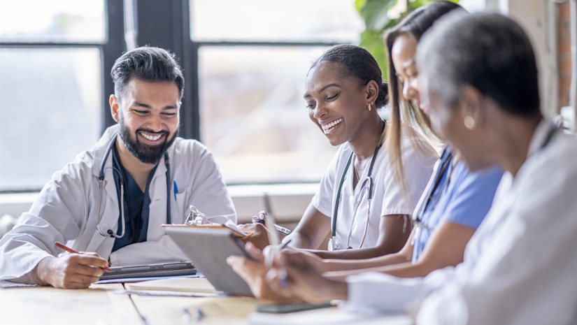 Small group of four medical professionals sit around a boardroom table
