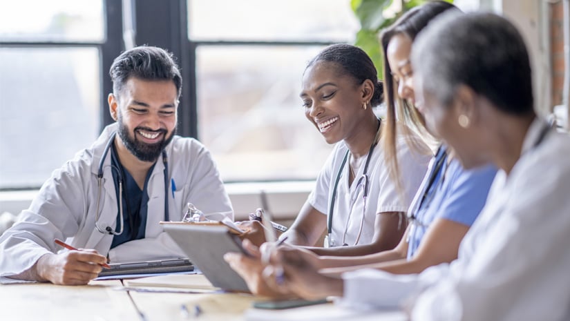 Small group of four medical professionals sit around a boardroom table