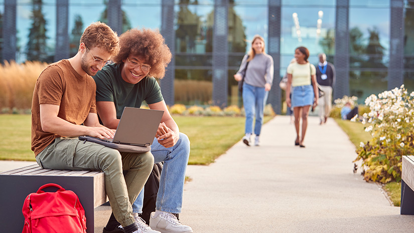 Male University Or College Students Sitting Outdoors On Campus Talking