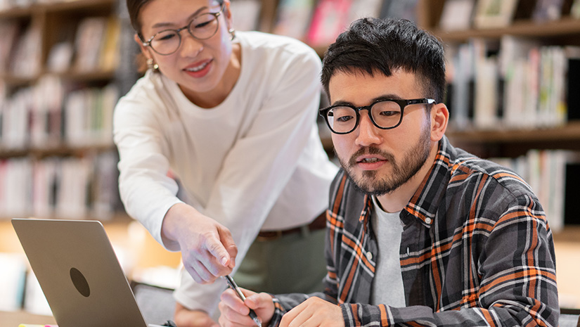 Professor talking to a student in a library