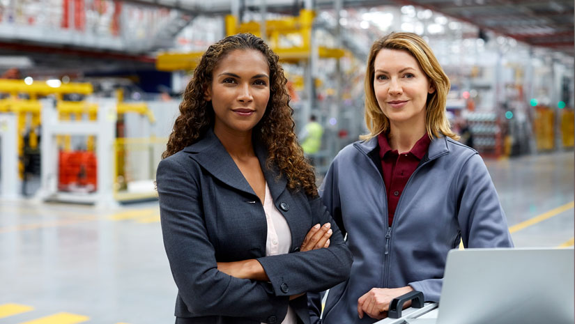 Portrait of confident engineers with laptop at car plant.