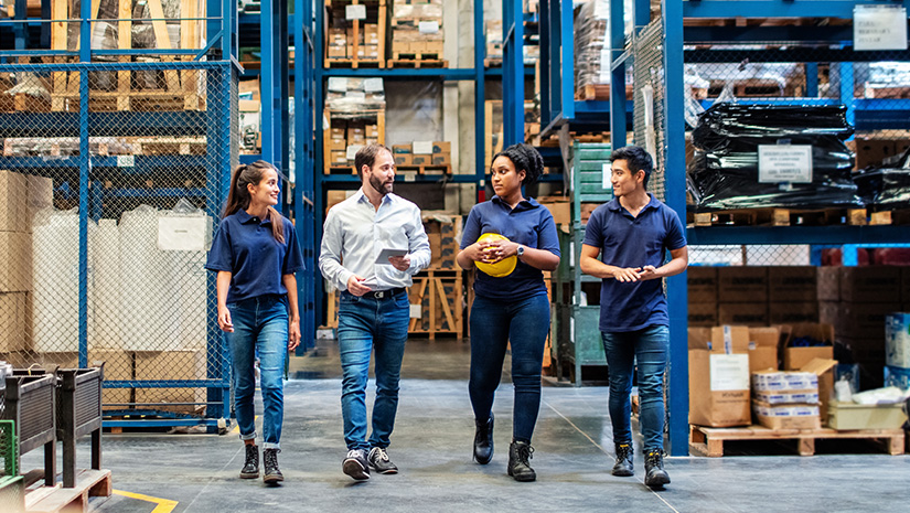 Warehouse employees walking through aisle and talking
