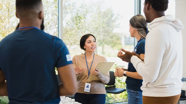 Diverse volunteers listen to female food drive coordinator
