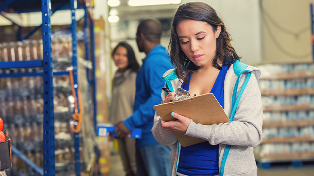 Young woman taking inventory of donations in food bank warehouse