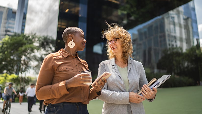 Business women talking while walking outdoors