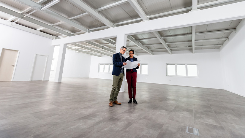 Businesspeople Meeting To Look At Plans In Empty Office